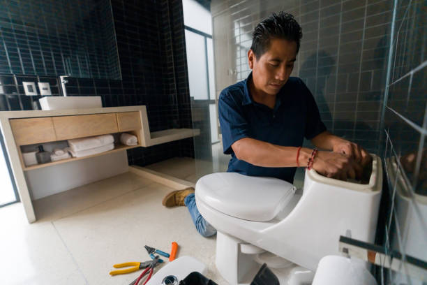 Latin American plumber fixing a toilet in the bathroom - home repair concepts