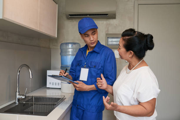 Mature Vietnamese woman talking to plumber in her kitchen