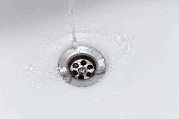 water flowing from faucet into sink drain
